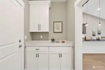 Upper & lower cabinets and laundry sink on one side of the utility room.