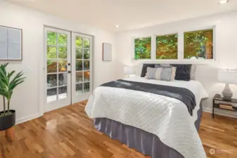 One of two main floor bedrooms, also with hardwood floors, french doors and nice views into the landscape.