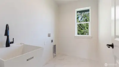 Laundry room with tile flooring and utility sink.