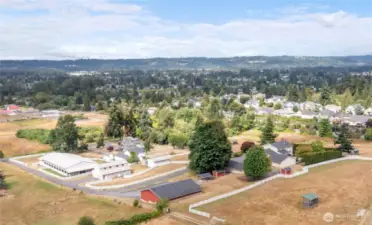 Overhead view of House & 2 garages on the right, red 10 car garage bottom middle, barn & equipment storage building towards the left & 60X120 covered arena on left with asphalt driveway. Top of picture on left is Tacoma & Edgewood @ top right. Valley in middle of picture with trees