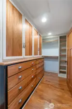 Walk in closet with plenty of storage drawers/cabinets built in and clothes hanging on each end of closet
