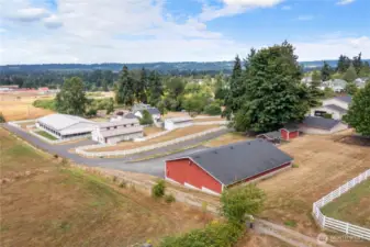 Picture from left side of property showing paved driveway leading past arena, barn & storage bldg, 10 car heated garage & up to 4 car/3 car garages and 2 car attached garage/home