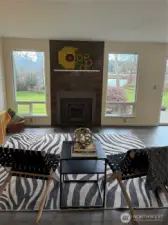 Living room features grand picture windows and wood stove for cool evenings, vinyl plank flooring throughout.
