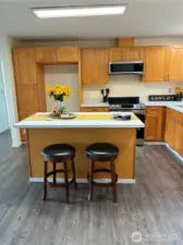 Fully updated kitchen with quartz counters, under-mount sink, wood cabinetry and island with eating bar.