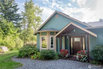 Beautiful covered entry porch with elegant wood doors and side windows.