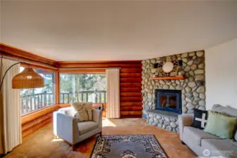 Rustic river rock gas fireplace adds warmth and character to the log home.