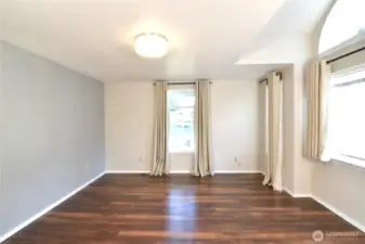 light-filled primary bedroom with large windows and decorative half-moon window