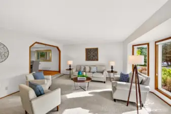 An expansive living room with generous wall space for art and media, plus a large window that brings in natural light. The layout offers flexible options for gathering, relaxing, or creating a quiet reading area.