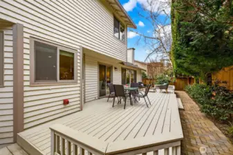 Expanded deck footprint with wide usable space and a natural connection to the side yard walkway. A great setup for hosting, with privacy provided by fencing and evergreen screening.