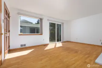 This freshly painted living room features a slider out to the patio and to the garage. Laminate flooring is easy to clean and maintain. Lots of light coming in, which is great for house plants!