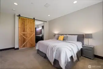 Barn doors lead to the en-suite bathroom and walk-in closet for a modern rustic touch.