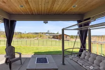 Drapery-style shades surround the covered patio, creating a cozy outdoor living space. A custom dog-safe fence encloses the area.