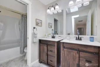 Hall bathroom with double vanities has a skylight