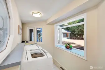 Laundry room located off of a corridor with storage closets