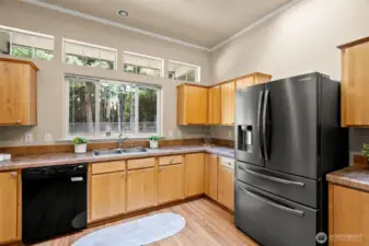Large windows, skylights, and recessed lighting floods the kitchen with natural light, creating a warm and inviting atmosphere for cooking and gathering.