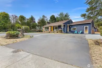 Full street-facing view with brick address sign post and gently perched position above the road.