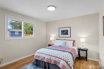 North bedroom overlooks the backyard with a wide western view—sunlight all afternoon and newly refinished oak floors underfoot.