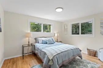 The south bedroom offers extra space and all-day light from its sunny corner windows, plus refinished hardwoods, new lighting, and updated closet doors.
