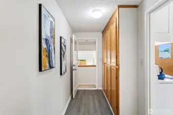 This second hallway connects the kitchen to the lower-level flex space and adds serious function with a full wall of oak cabinets, a second coat closet, and matching LVP flooring.
