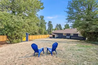 The upper terrace forms a natural gathering space, centered around a fire pit and surrounded by mature trees and dappled shade—a peaceful perch for outdoor connection.