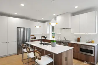 Chef's kitchen with SS appliances, Abodian cabinets, spacious island, quartz counters, and under-cabinet lighting.