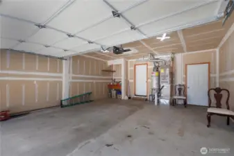 Garage with workbench in the corner. Door on left accesses the home, door on right goes out to side/back yard.