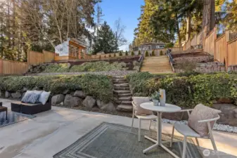 Fully fenced outdoor sanctuary with easy-care landscaping, an expansive levelled terraced backyard, a large patio for entertaining, a gardener's greenhouse, and a storage shed.