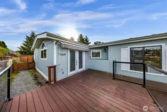 Approach the front of the home from the beautiful walk way and landscaping to a large deck and French doors to access to main entry to the home.