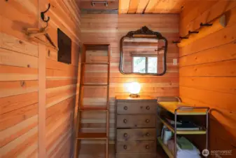 Interior of bunkhouse is all wood with ladder to a small loft