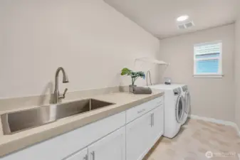 Large galley-style landry room with sink and foling area.