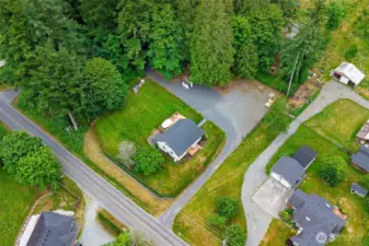 Aerial view showcasing the expansive, private lot surrounded by mature trees—offering ample space, a circular driveway, and secluded charm just minutes from town amenities.