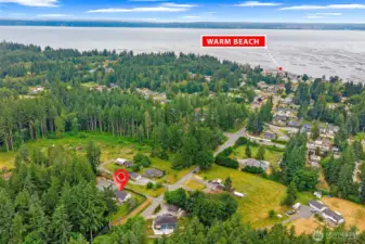 Aerial perspective highlighting the property’s prime location just minutes from Warm Beach—enjoy coastal living with a peaceful, wooded setting and easy access to community amenities.