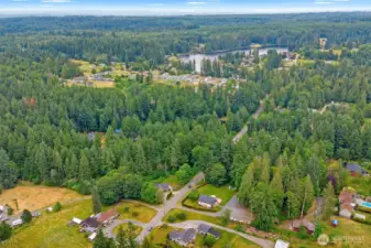 Expansive aerial view showcasing the property's serene wooded surroundings and proximity to nearby lakes and residential communities