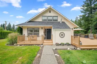 Inviting front entry welcomes you with charming curb appeal, a covered porch, and beautifully landscaped pathways—leading to an expansive deck perfect for outdoor living.
