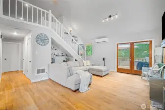 Bright and airy living room with vaulted ceilings, hardwood floors, and French doors leading to the deck—perfectly blending indoor comfort with outdoor charm.