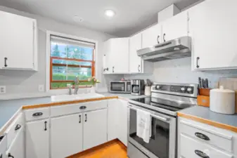 Charming kitchen with white cabinetry and a sun-filled window above the sink offering serene backyard views.