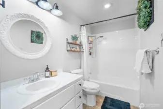 Charming full bathroom featuring a classic white vanity, tile shower/tub combo, and stylish accents for a clean, inviting feel.