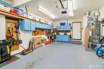 One car garage is deep with cupboards and shelving.