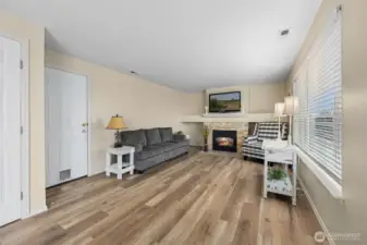 View from the kitchen/dining area looking into the family room, featuring a warm gas fireplace and a door to the garage.