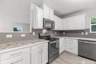 Plenty of counter and cabinet space in this sunny, bright kitchen. Updated stainless appliances. Full height tile backsplash, handsome, modern hardware bring it all together.