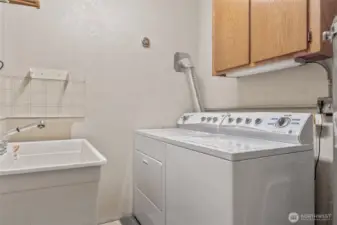 Lower level laundry with basin and storage cabinets.