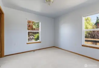 In the guest bedroom, two windows perfectly frame the lush beauty of the trees just beyond, inviting nature’s calm right inside.