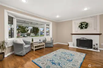 Formal living room with wood burning fireplace and bay windows.