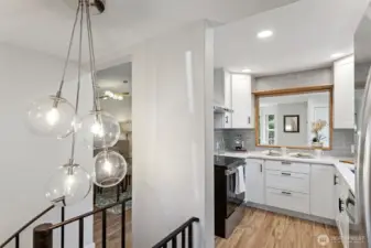From the spiral stair landing: the globe cluster pendant, the dining room beyond, the kitchen beside it. One last look before the stairs take you down.