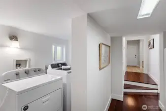 The spiral stair lands here — laundry to the left, daylight corridor straight ahead.