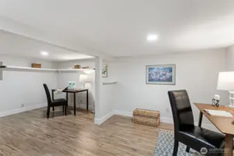 The full picture: two zones, built-in white shelving, LVP flooring. No windows — which makes it a natural media room — but more usable square footage than the bedroom count suggests.