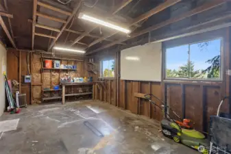 Straight from the primary bedroom into a single-car garage with high ceilings, built-in workbench, sub-panel, and two windows. A real workshop.