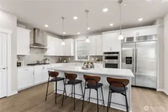 Gourmet kitchen featuring an expansive island, quartz countertops, 48" counter depth refrigerator, gas cooktop and built-in microwave and oven. Designed for both everyday living and entertaining.