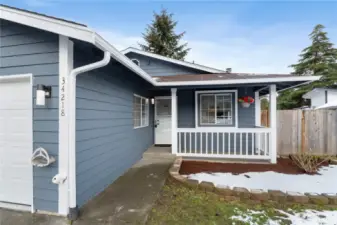 Nicely covered cement porch to guard you & your guests from the elements as you enter the home.  East gate to the dog run is in view and to the right of the white railing.