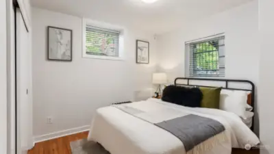 Cozy bedroom big enough for queen bed and nightstands with closet and natural light shining in